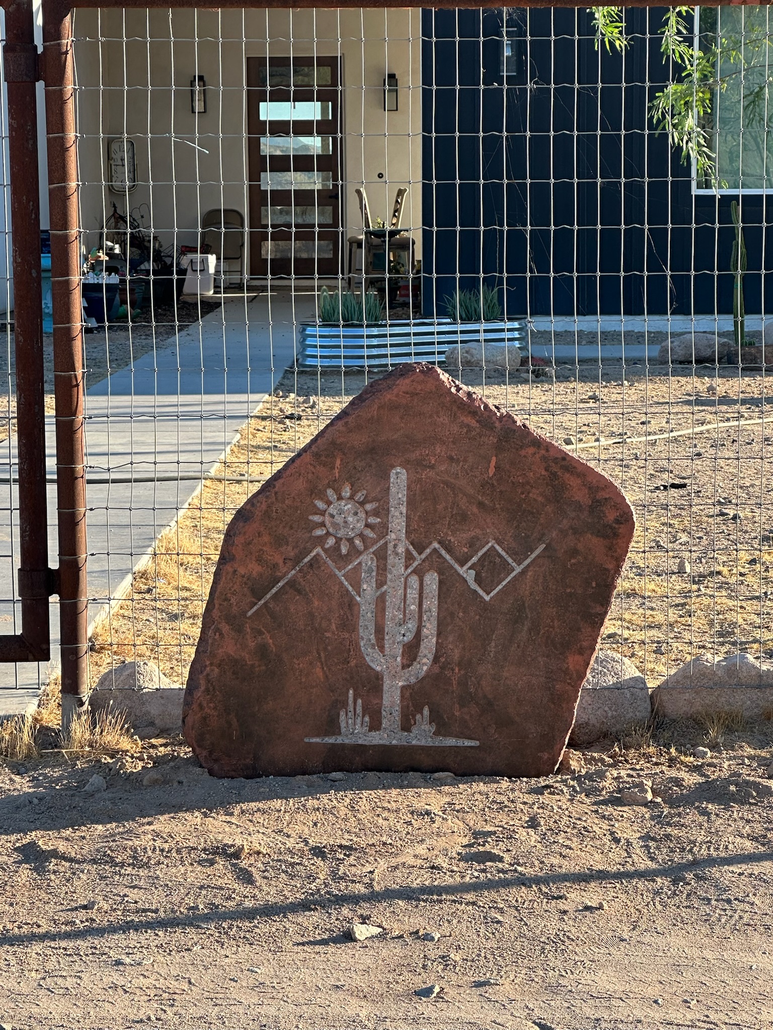 Natural stone engraved with a saguaro cactus, mountains, and desert sun