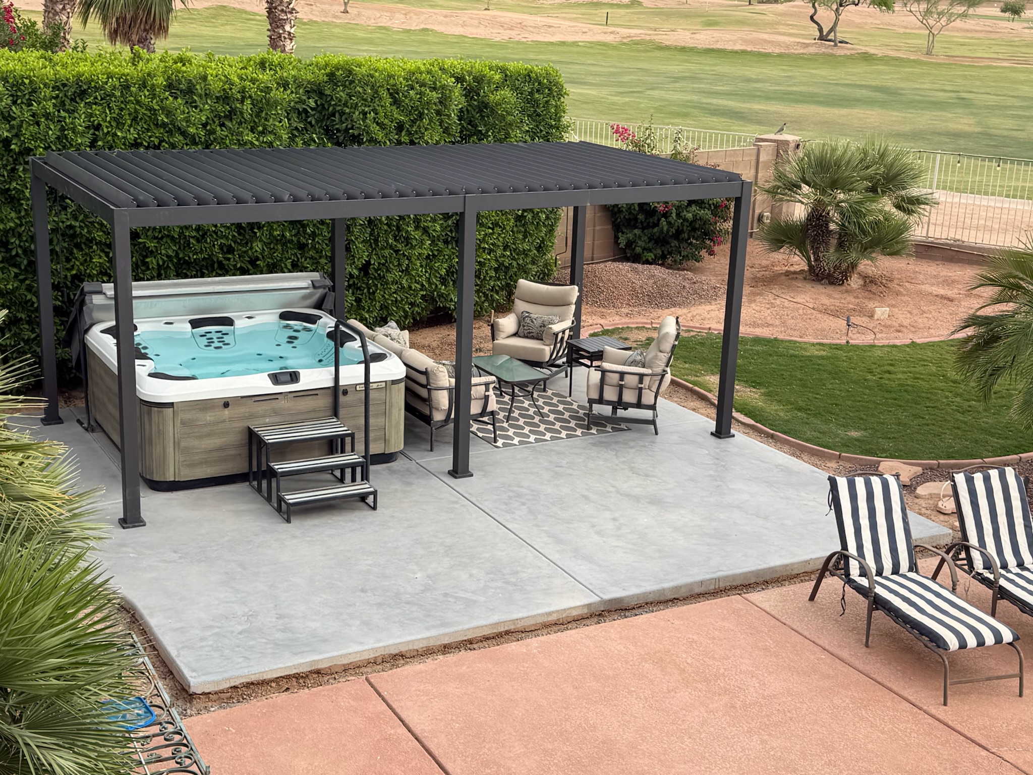 Stained concrete patio with a Jacuzzi, seating area, and modern gazebo